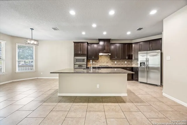 a large kitchen with stainless steel appliances kitchen island granite countertop a refrigerator a stove a sink and a sink