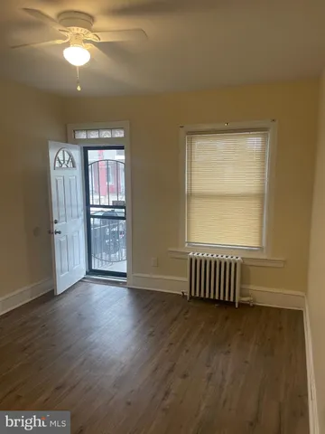 an empty room with wooden floor cabinet and windows