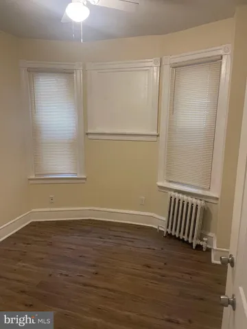 an empty room with wooden floor cabinet and windows