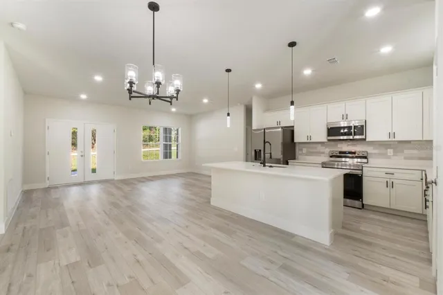 a large white kitchen with lots of counter space wooden floor and appliances