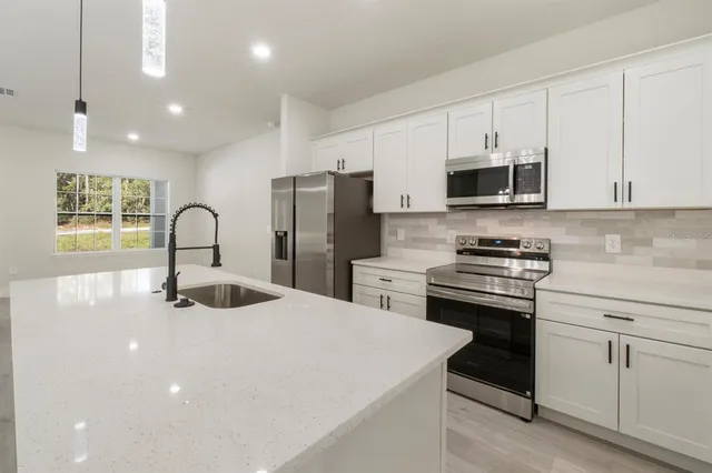 a kitchen with kitchen island a sink stainless steel appliances and cabinets