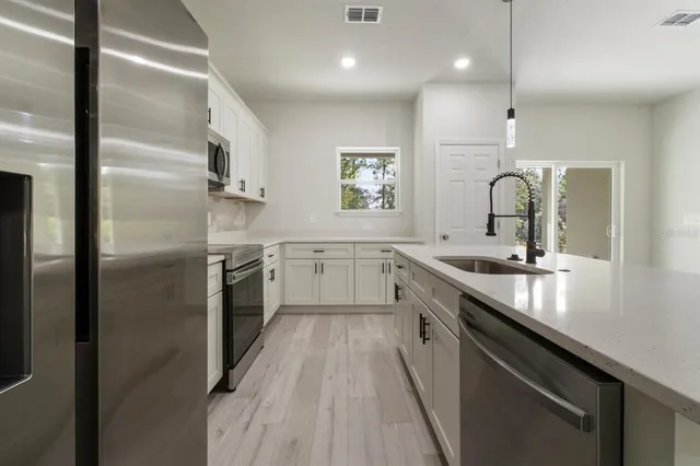 a kitchen with stainless steel appliances granite countertop a sink a stove and a refrigerator