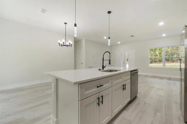 a kitchen with a sink chandelier and wooden floor