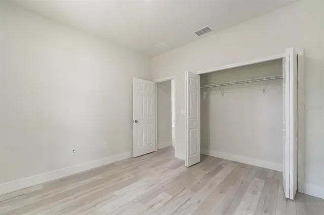 a view of an empty room with wooden floor and closet