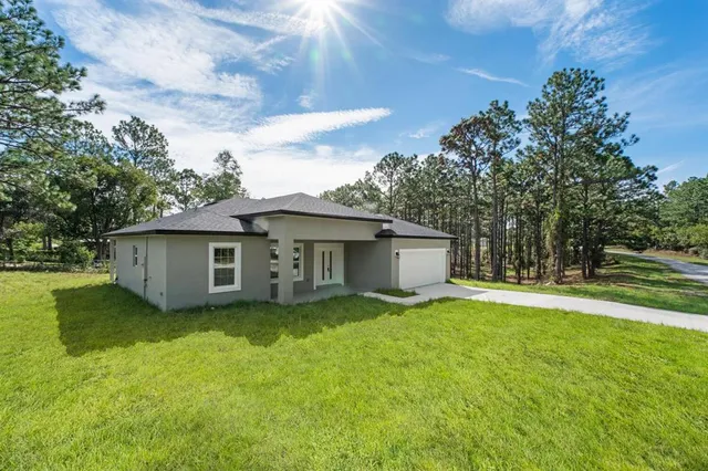 a view of a house with a yard and a large tree