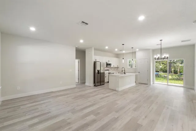 a view of a kitchen with kitchen island wooden floor center island and stainless steel appliances