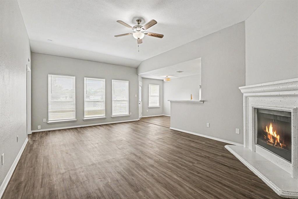 138 Kings Way Drive Rhome, TX 76078 - Photo 4 of 16 an empty room with wooden floor fireplace fan and windows