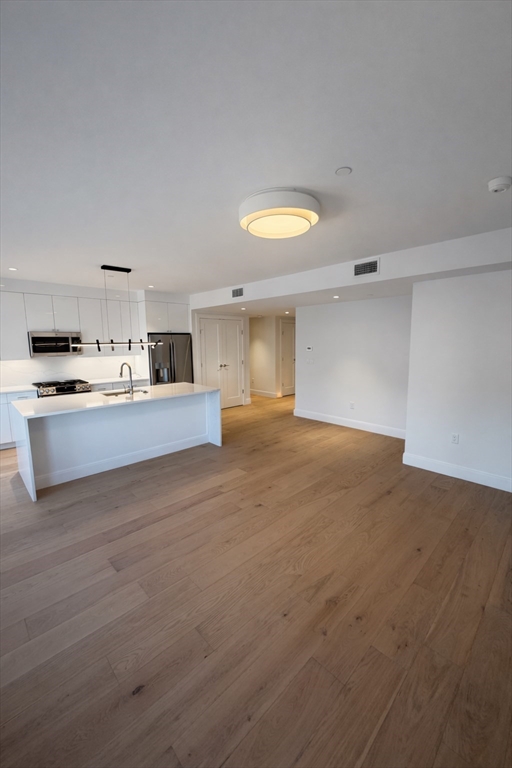 65 L Street, Unit 1 Boston, MA 02127 - Photo 2 of 9 a large white kitchen with kitchen island a sink stainless steel appliances and cabinets
