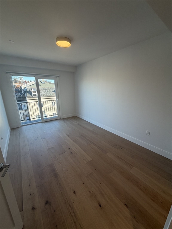 65 L Street, Unit 1 Boston, MA 02127 - Photo 6 of 9 an empty room with wooden floor and windows
