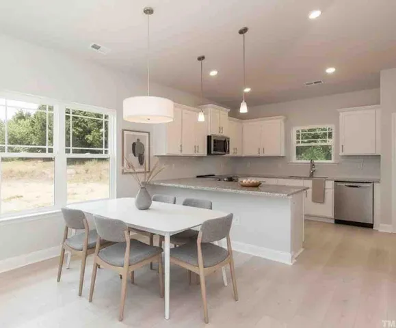 a kitchen with a dining table chairs and white cabinets
