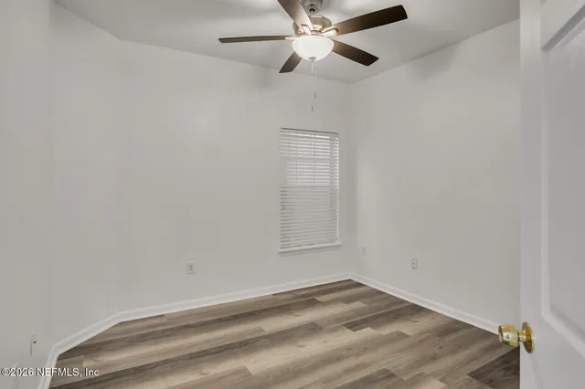 an empty room with a window and ceiling fan