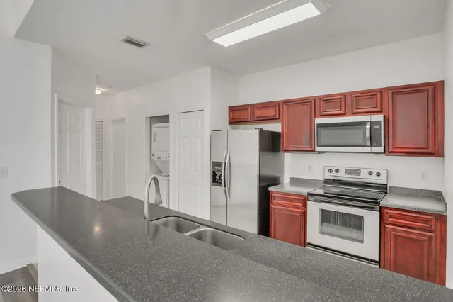 a kitchen with stainless steel appliances granite countertop a refrigerator a stove and a sink with wooden floor