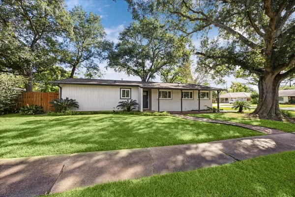 a front view of a house with a garden and trees