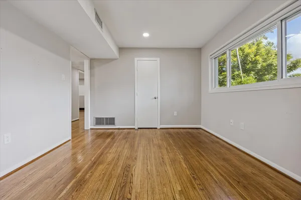 a view of an empty room with wooden floor and a window