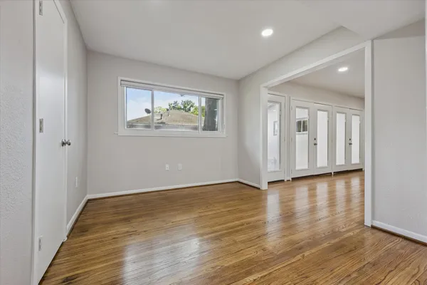a view of an empty room with wooden floor and a window