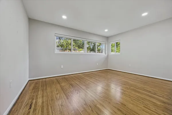 an empty room with wooden floor and windows