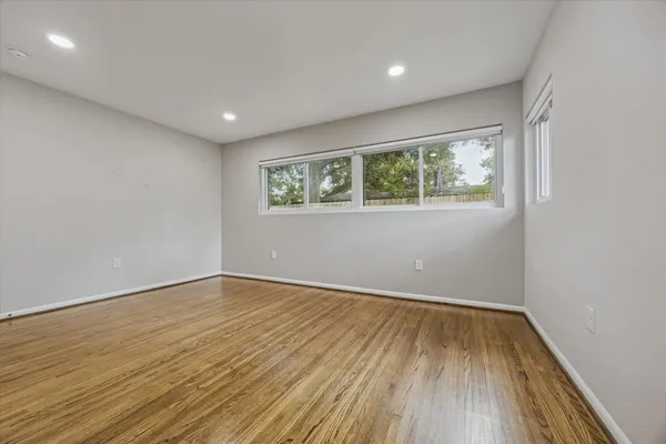 an empty room with wooden floor and windows