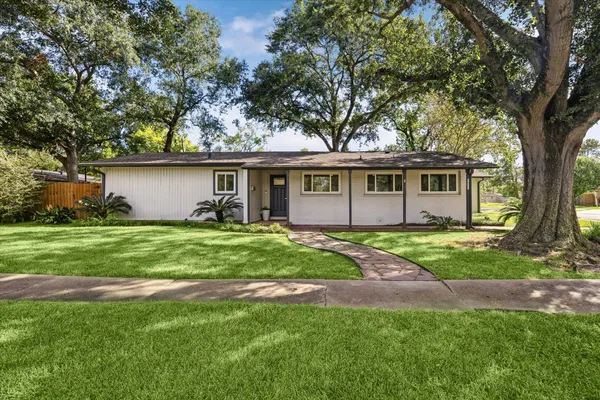 a view of a house with a big yard and large trees