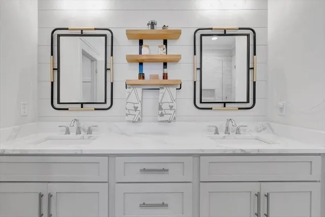 a bathroom with double vanity sinks and two mirror