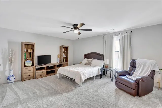 a spacious bedroom with a bed a couch and a flat screen tv