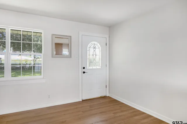 an empty room with wooden floor and windows