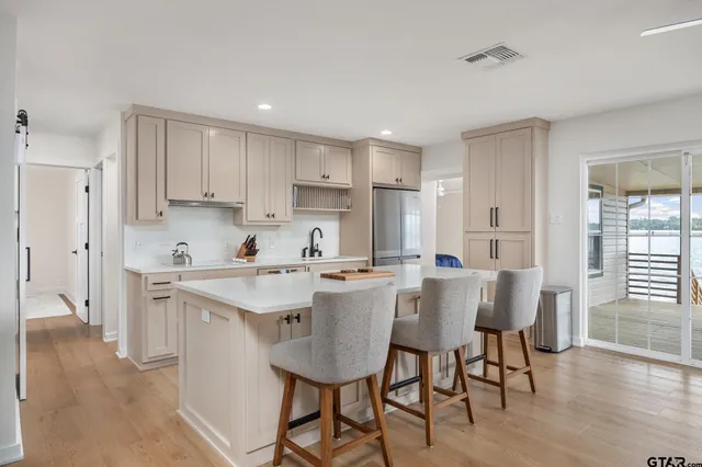 a kitchen with a dining table chairs wooden floor cabinets and appliances