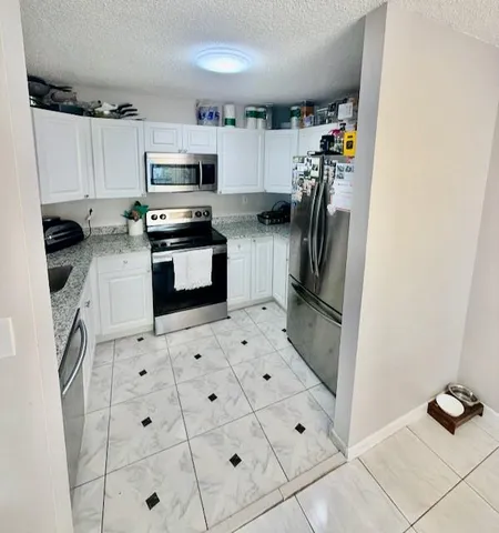 a kitchen with granite countertop a refrigerator and a stove top oven