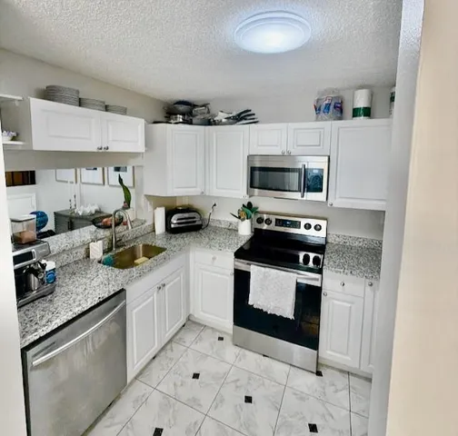 a kitchen with granite countertop a stove sink and cabinets