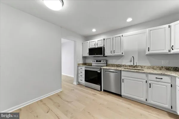 a kitchen with granite countertop white cabinets and stainless steel appliances