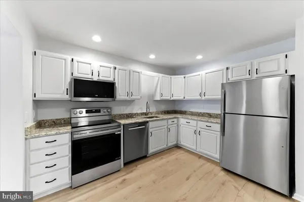 a kitchen with stainless steel appliances granite countertop a refrigerator stove a sink and a microwave