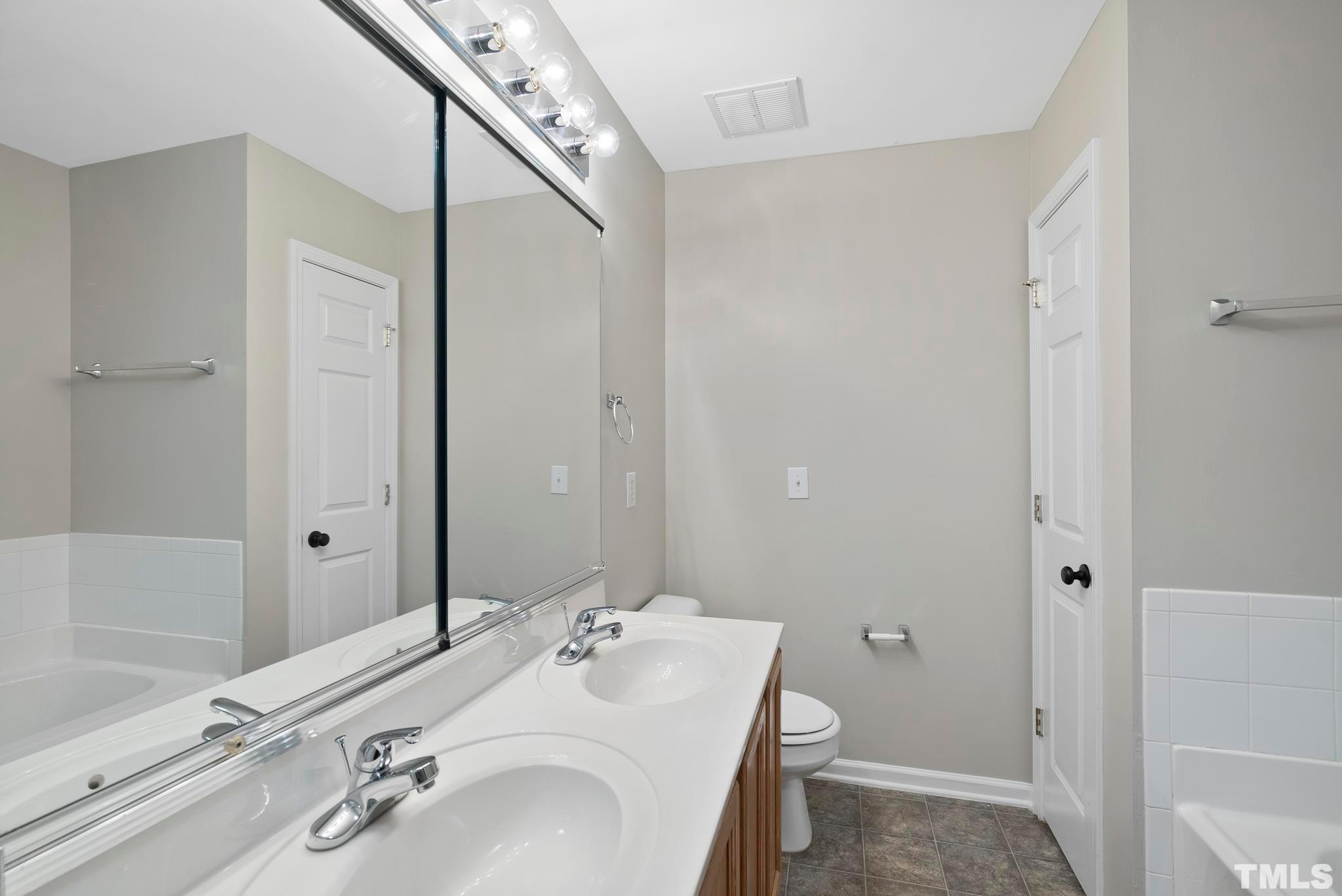 3011 Barrymore Street, Unit 107 Raleigh, NC 27603 - Photo 23 of 33 a bathroom with a granite countertop sink toilet a shower and a mirror