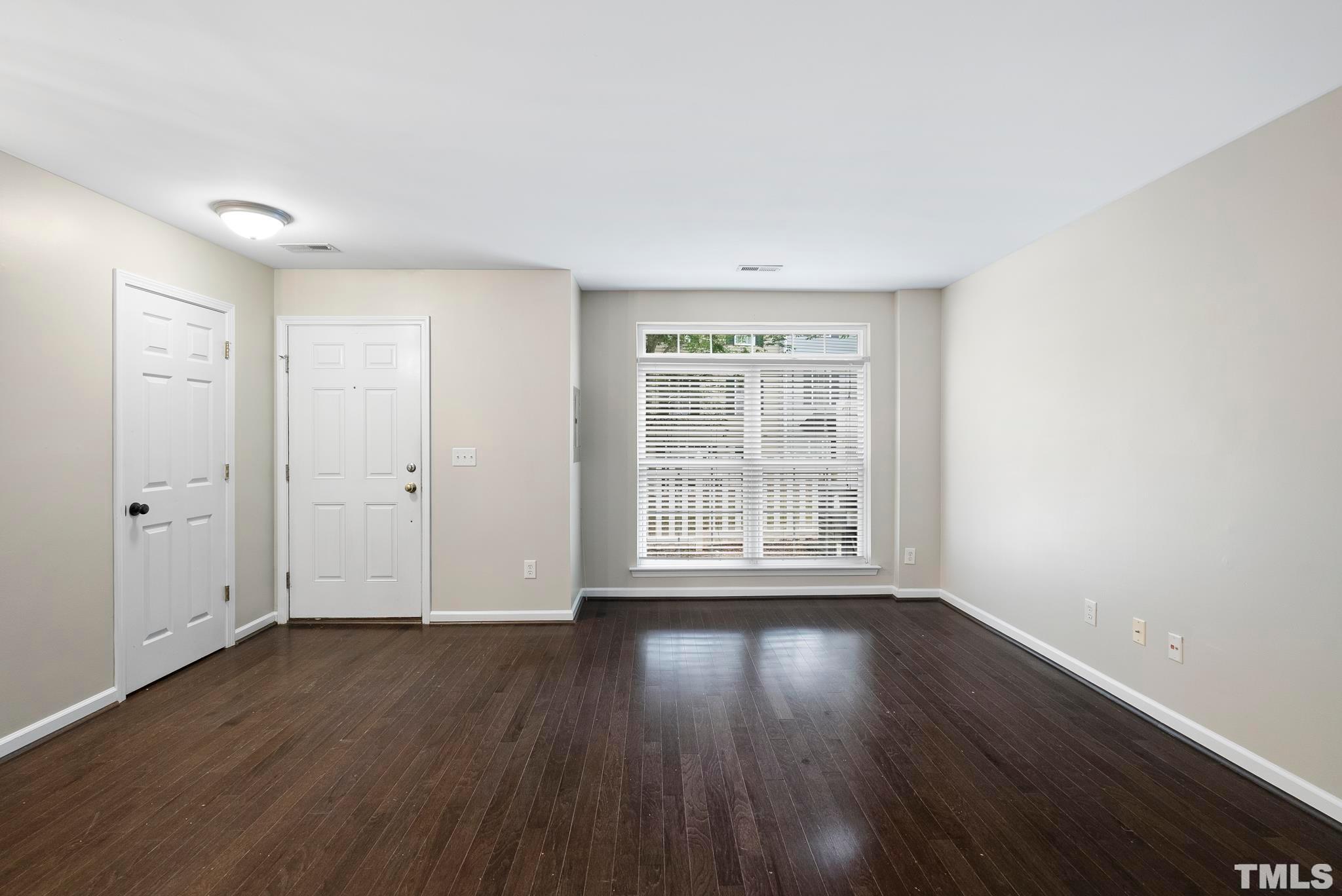3011 Barrymore Street, Unit 107 Raleigh, NC 27603 - Photo 8 of 33 a view of an empty room with wooden floor and a window