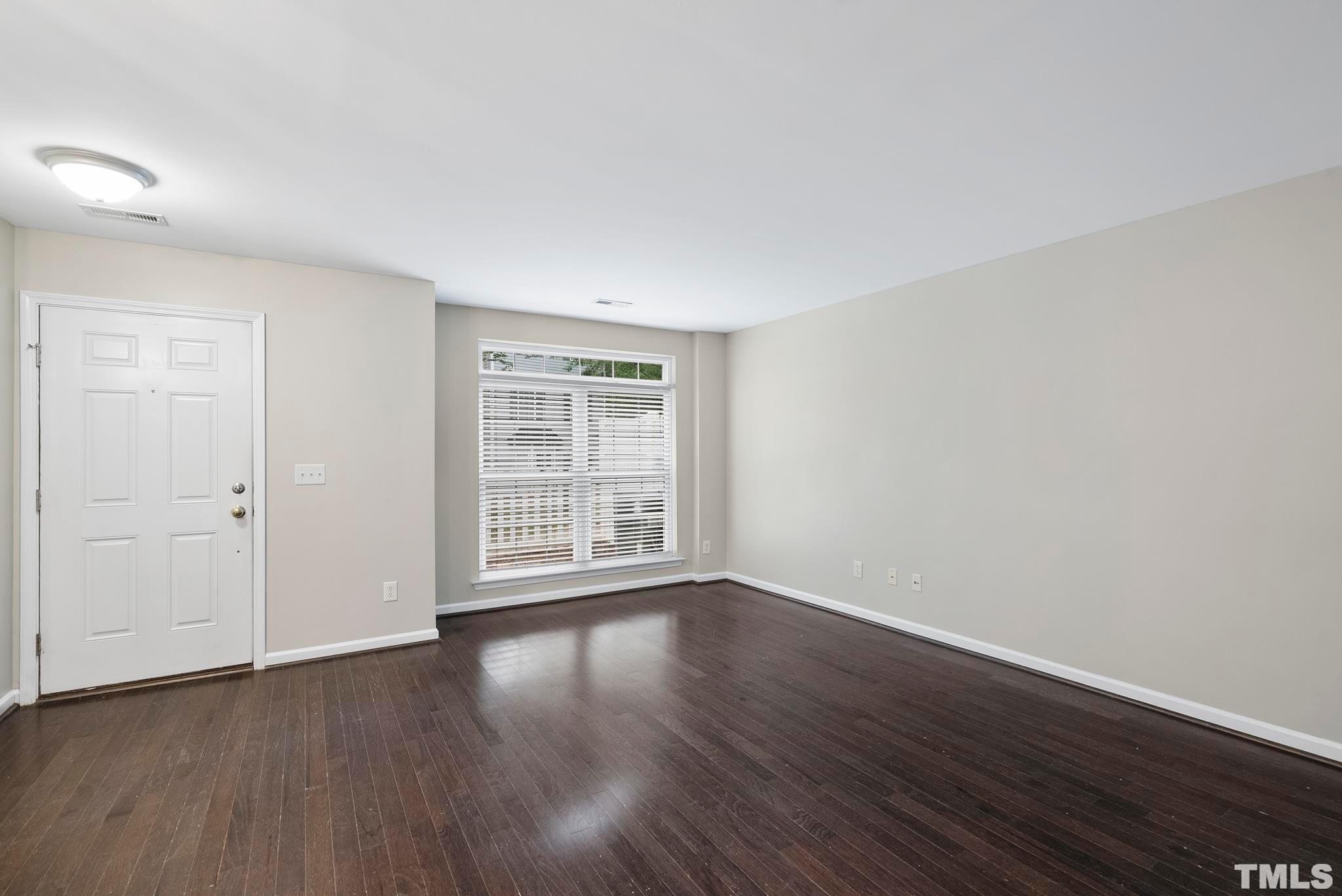 3011 Barrymore Street, Unit 107 Raleigh, NC 27603 - Photo 9 of 33 a view of an empty room with wooden floor and a window