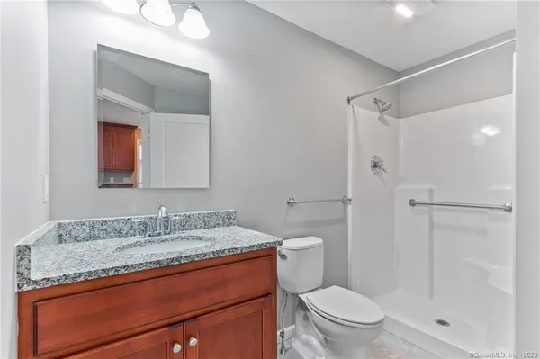 a bathroom with a granite countertop sink toilet and shower