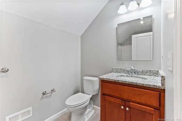 a bathroom with a granite countertop sink toilet and mirror