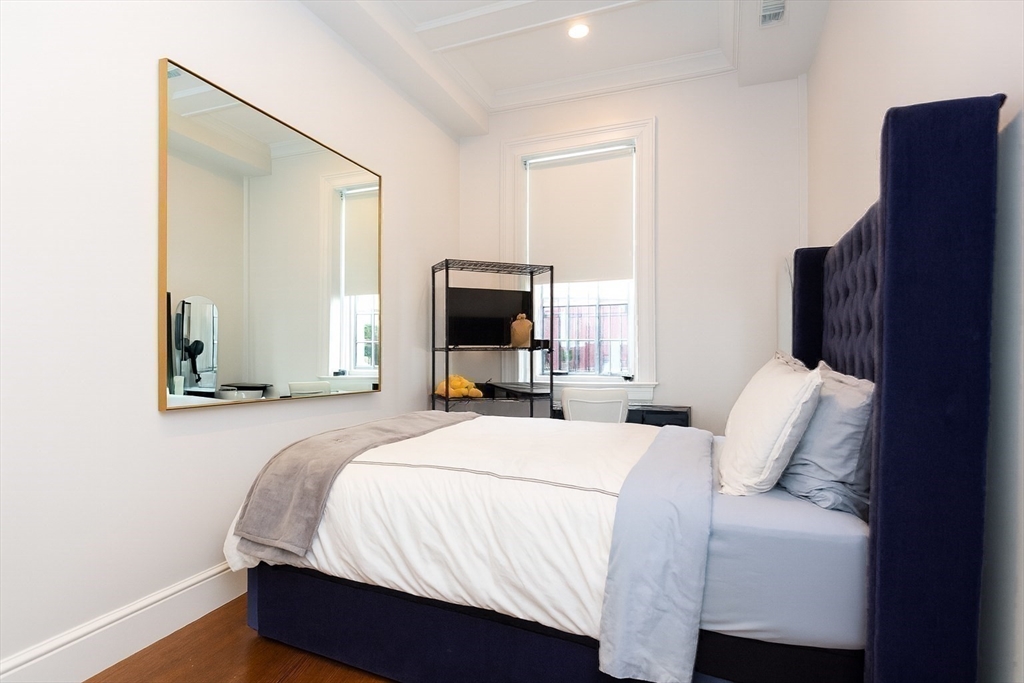 288 Commonwealth Avenue, Unit 1 Boston, MA 02115 - Photo 21 of 36 a bedroom with a bed flat screen tv and a mirror