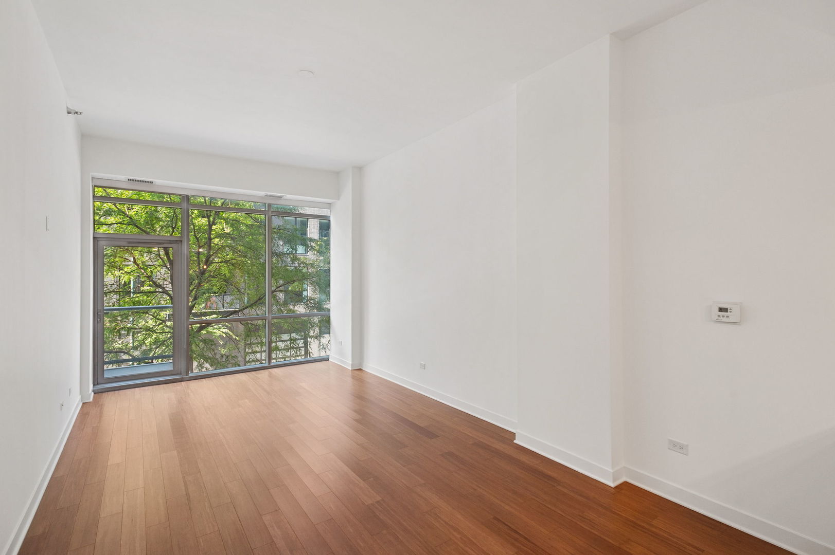 125 South Green Street, Unit 209A Chicago, IL 60607 - Photo 4 of 16 a view of an empty room with wooden floor and a window