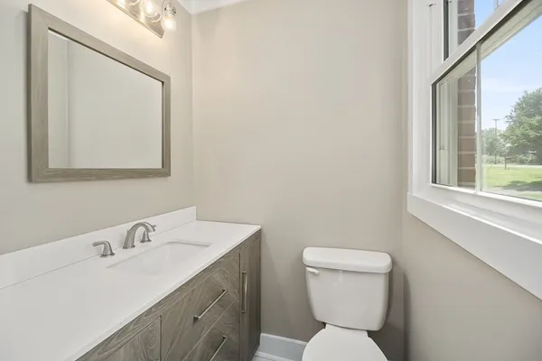 a bathroom with a toilet a sink a mirror and vanity