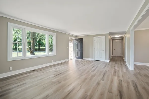 a view of an empty room with wooden floor and a window