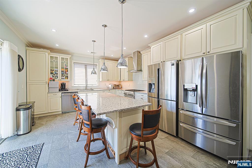 897 Virgil Avenue Ridgefield, NJ 07657 - Photo 28 of 50 a kitchen with stainless steel appliances a refrigerator a stove a sink and white cabinets with wooden floor
