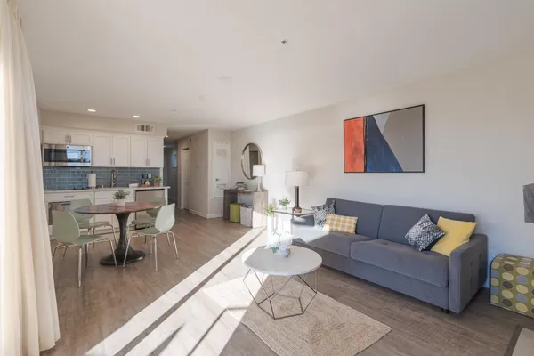 a living room with furniture kitchen view and a wooden floor
