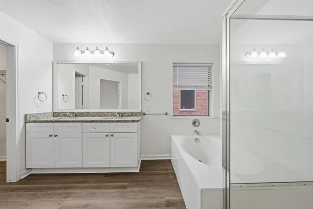 a spacious bathroom with a granite countertop sink a mirror and a bathtub