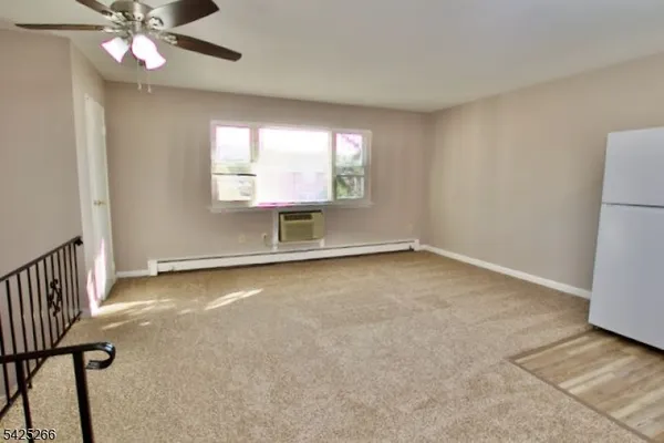 an empty room with chandelier fan and windows