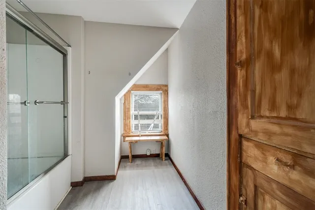 a view of a hallway with bathroom and wooden floor
