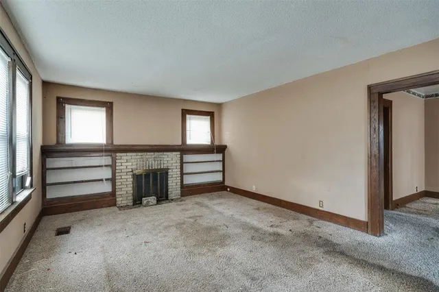 an empty room with a fireplace and windows