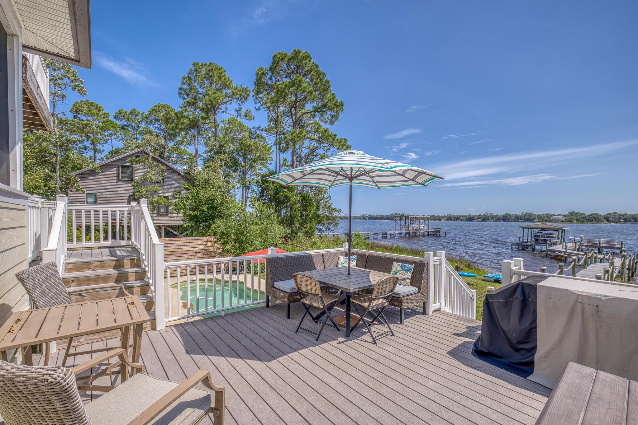 7121 Wells Avenue Navarre, FL 32566 - Photo 70 of 125 a view of a roof deck with table and chairs under an umbrella with wooden floor