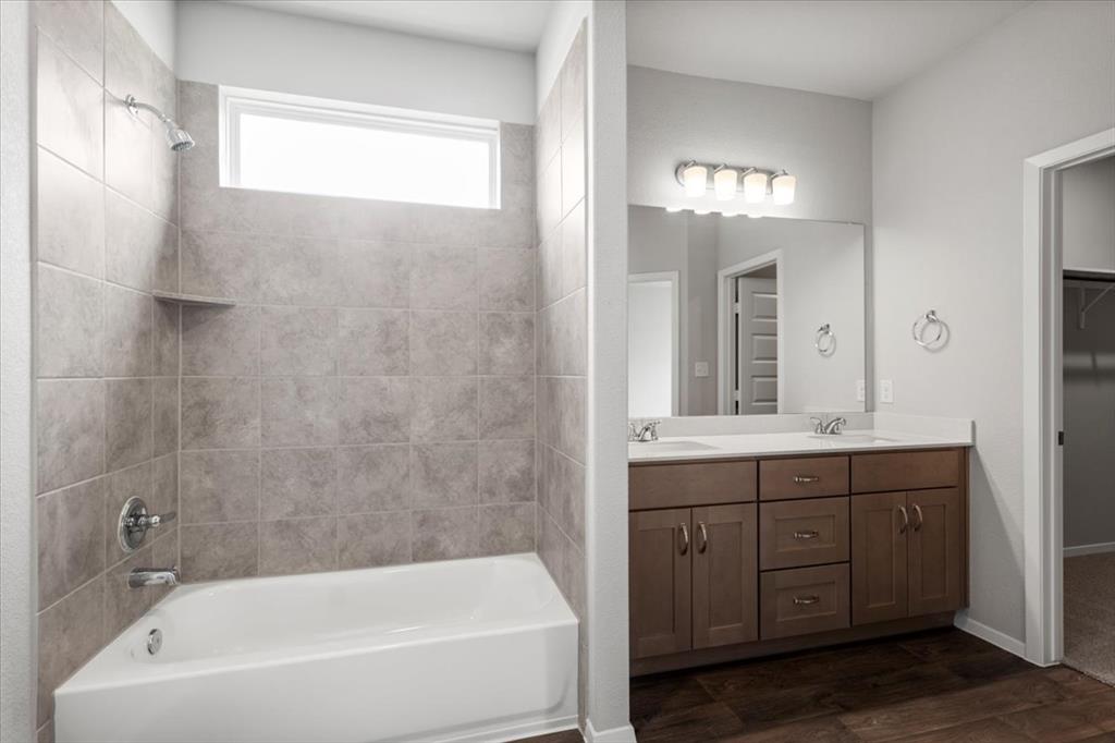 2707 Totley Road Manor, TX 78653 - Photo 20 of 39 Bathroom featuring double vanity, tub / shower combination, dark wood-style flooring, and a walk in closet