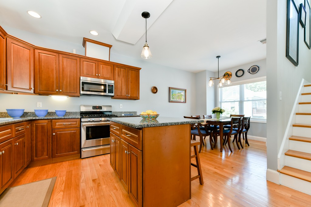 2 Mendell Way, Unit 2 Boston, MA 02130 - Photo 5 of 12 a kitchen with stainless steel appliances granite countertop wooden cabinets a stove a sink a dining table and chairs with wooden floor