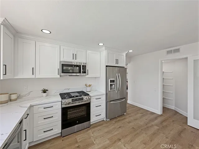 a kitchen with stainless steel appliances white cabinets and a refrigerator
