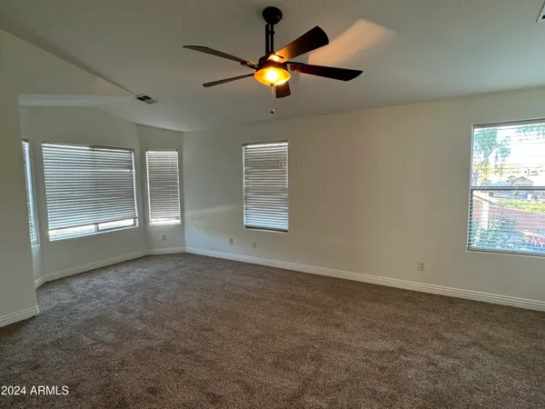 an empty room with windows and fan